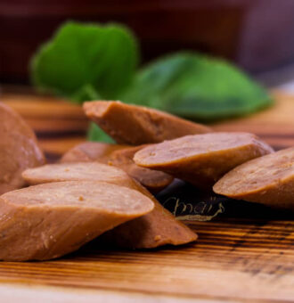 Cuisses de foie gras en tranches sur planche en bois avec basilic en arrière-plan.