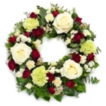 Rond de fleurs de cérémonie avec roses blanches, rouges et hortensias vert clair. Design floral élégant pour mariage ou commémoration.