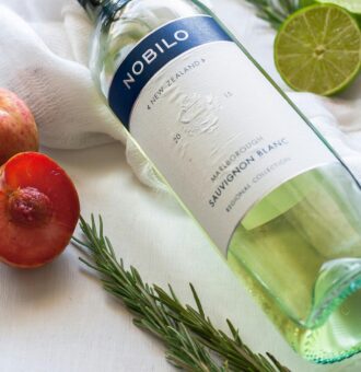 Fiole de gin Nobilo avec citron vert, pommes et herbes aromatiques.